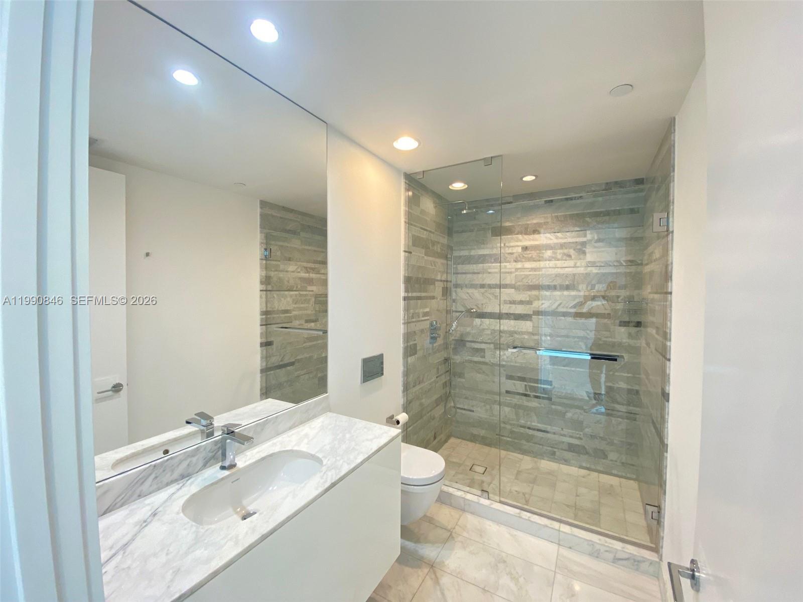 10203 Collins Avenue, Unit 905 Bal Harbour, FL 33154 - Photo 17 of 35 a bathroom with a granite countertop sink a toilet and shower