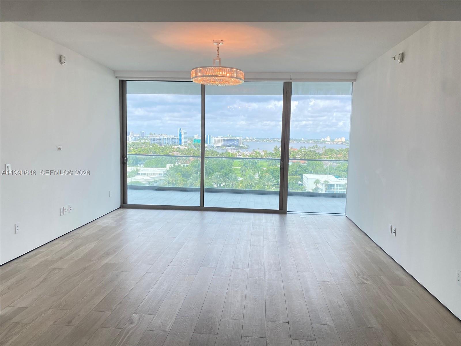 10203 Collins Avenue, Unit 905 Bal Harbour, FL 33154 - Photo 5 of 35 a view of an empty room with wooden floor and a window
