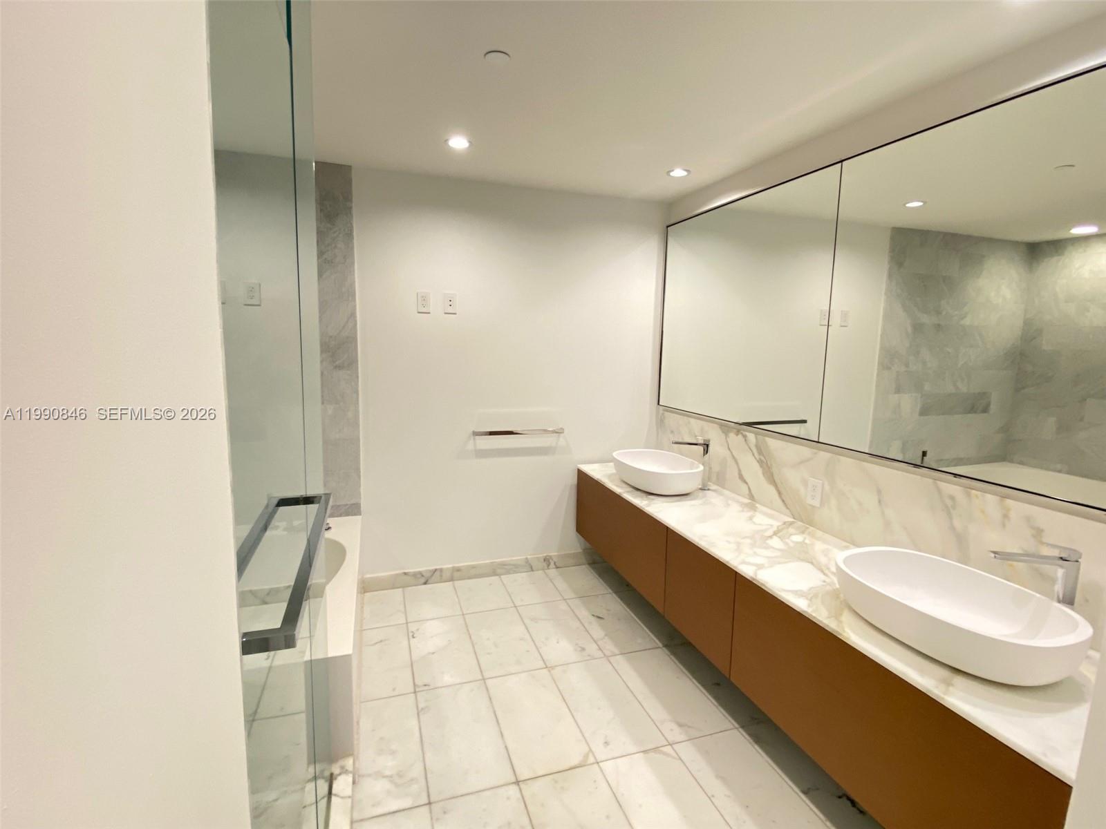 10203 Collins Avenue, Unit 905 Bal Harbour, FL 33154 - Photo 10 of 35 a bathroom with a double vanity sink a mirror and a bathtub
