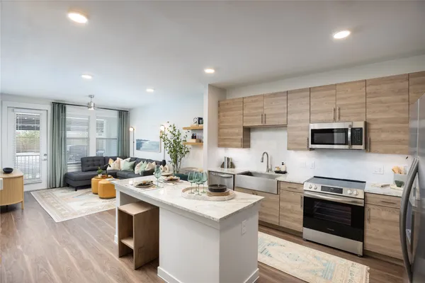 a kitchen with stainless steel appliances kitchen island granite countertop a sink dishwasher stove and refrigerator with wooden floor