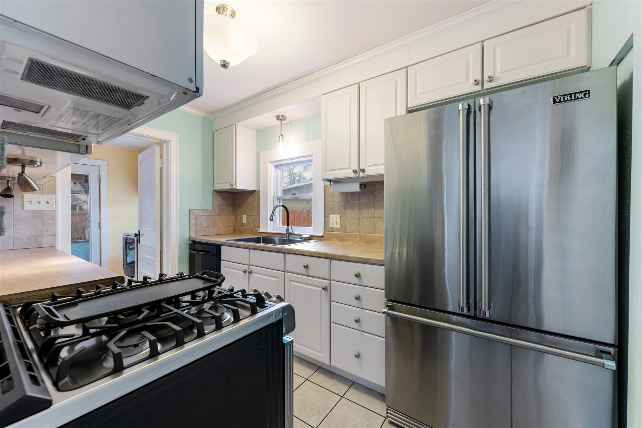 1218 South Myrtle Street Georgetown, TX 78626 - Photo 17 of 37 Kitchen with stainless steel appliances, light countertops, exhaust hood, white cabinets, and ornamental molding