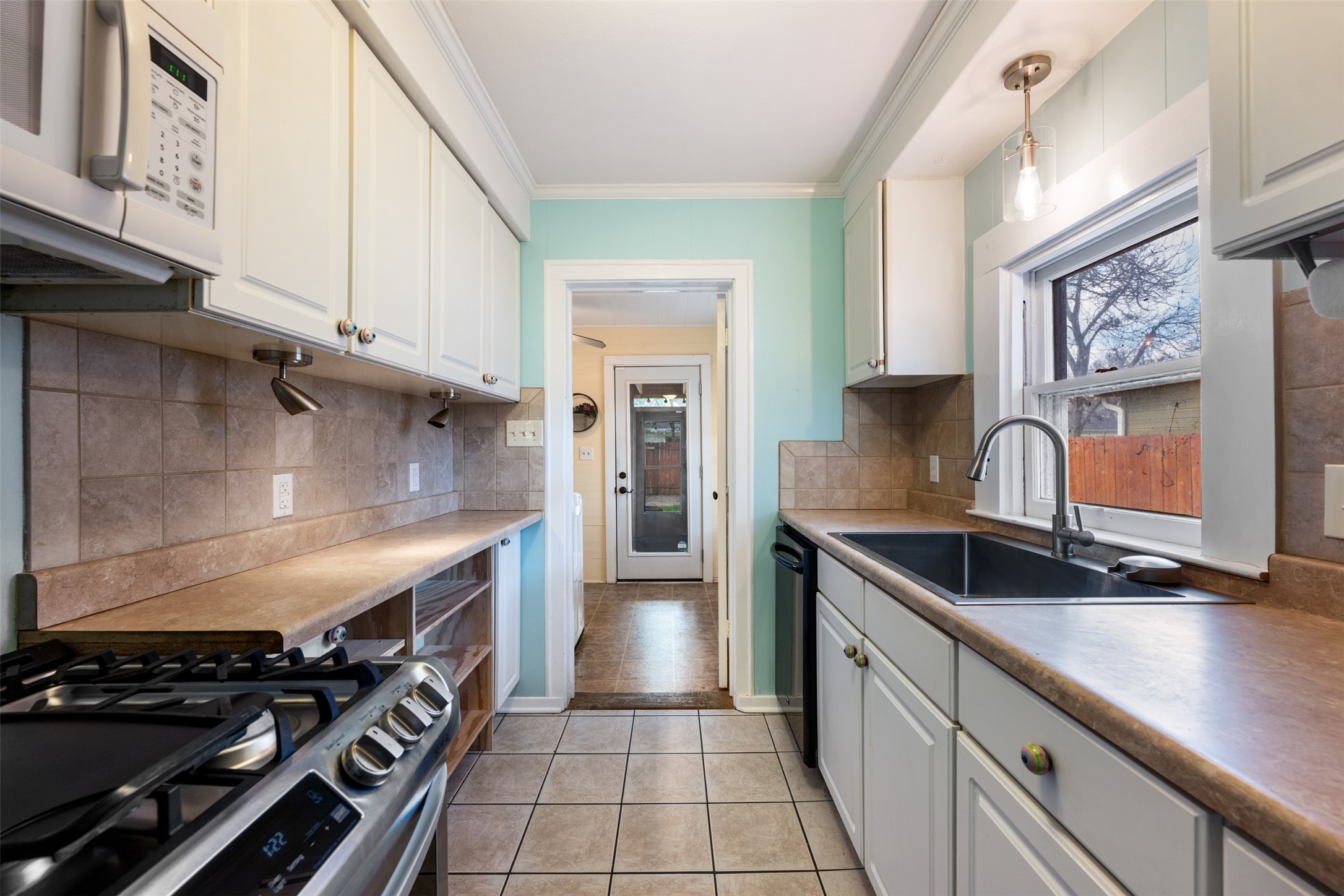 1218 South Myrtle Street Georgetown, TX 78626 - Photo 18 of 37 Kitchen with white microwave, ornamental molding, plenty of natural light, hanging light fixtures, and tasteful backsplash