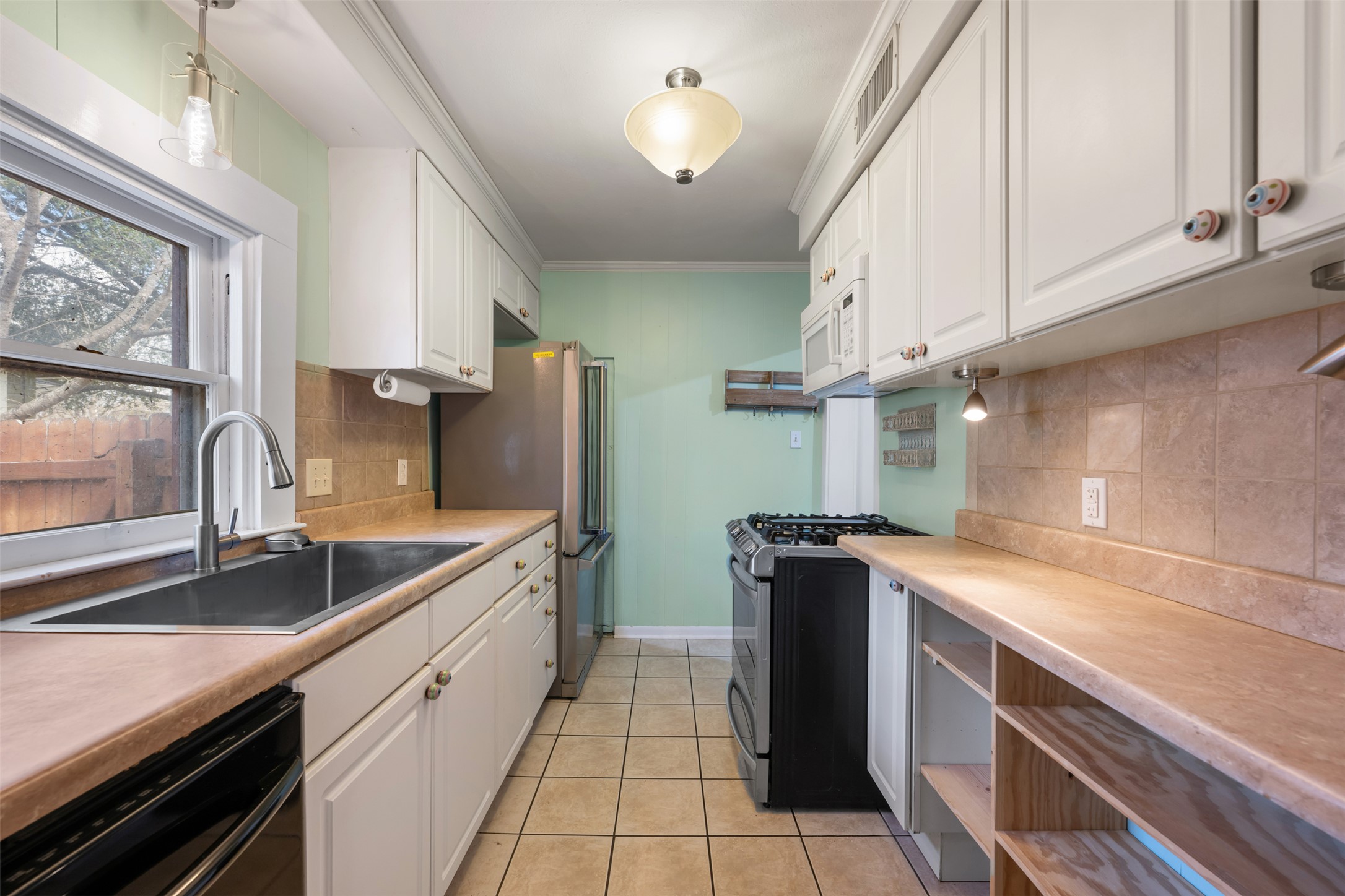 1218 South Myrtle Street Georgetown, TX 78626 - Photo 19 of 37 Kitchen with white cabinets, light countertops, range with gas cooktop, ornamental molding, and black dishwasher