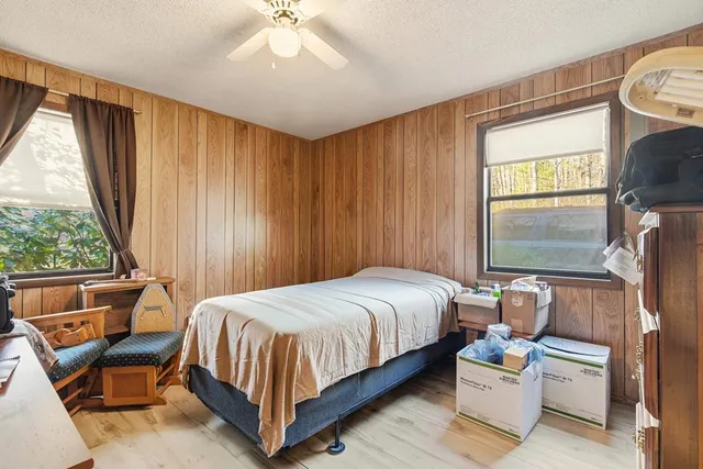 a bedroom with a bed wooden floor and window