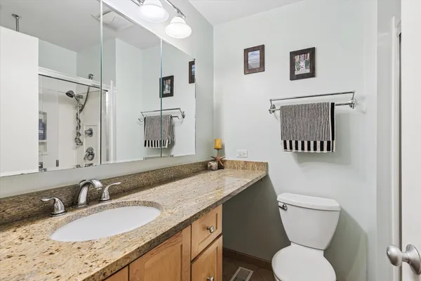 a bathroom with a granite countertop toilet sink and a mirror