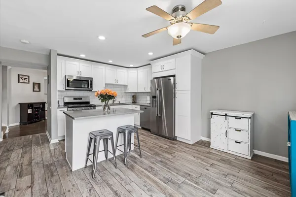 a kitchen with granite countertop a refrigerator oven a sink dishwasher and white cabinets with wooden floor