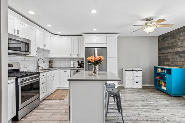 a kitchen with stainless steel appliances granite countertop a stove top oven a sink dishwasher and a refrigerator with wooden floor