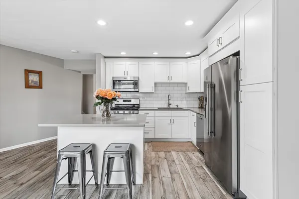 a kitchen with stainless steel appliances granite countertop a refrigerator sink and white cabinets