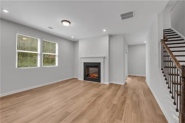 a view of an empty room with wooden floor fireplace and a window