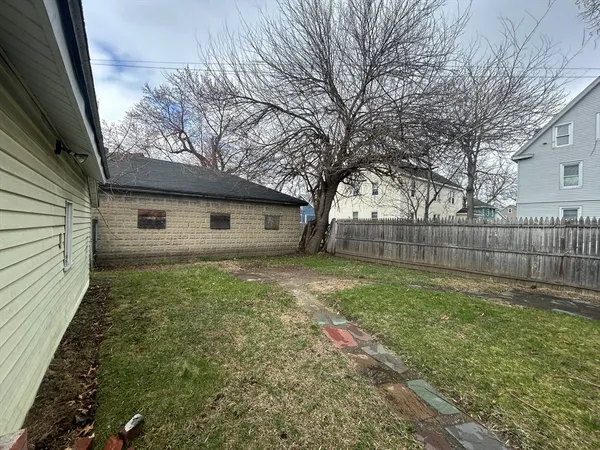 a view of a backyard with large trees and wooden fence