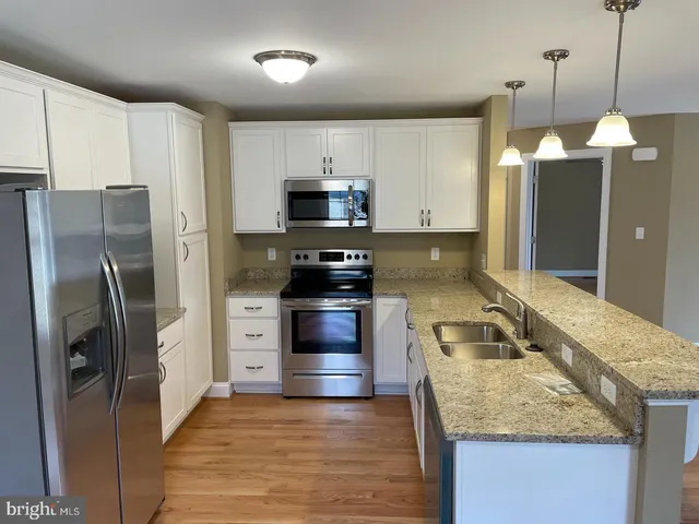 a kitchen with stainless steel appliances granite countertop a refrigerator a stove a sink and a microwave