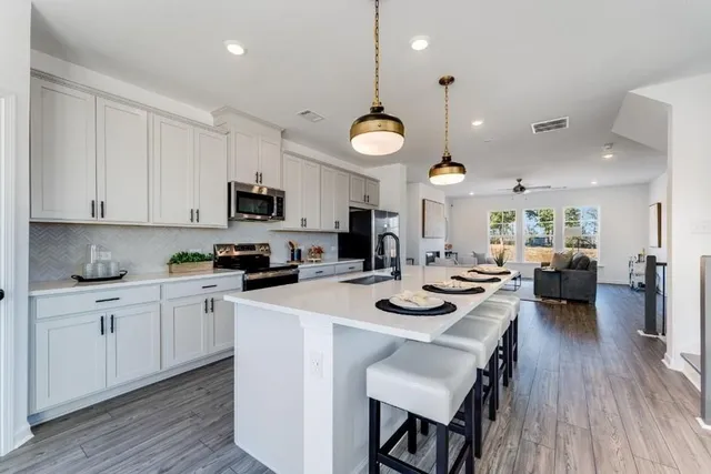 a kitchen with a sink a stove and chairs with wooden floor