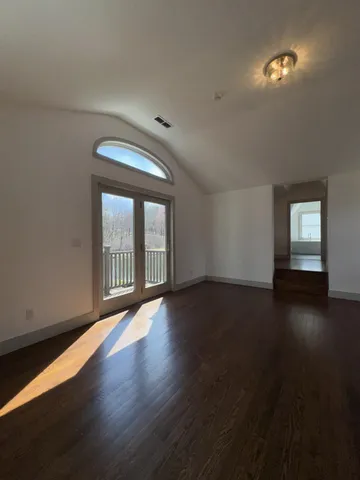 a view of empty room with wooden floor and windows