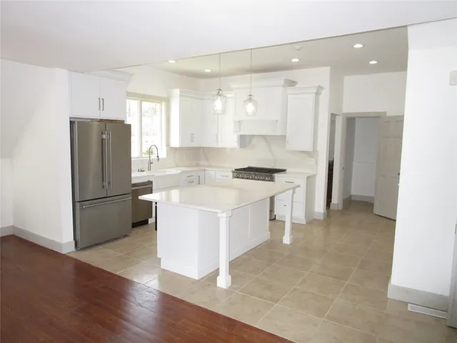 a kitchen with stainless steel appliances kitchen island a refrigerator sink and cabinets