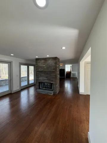 an empty room with wooden floor fire place and windows