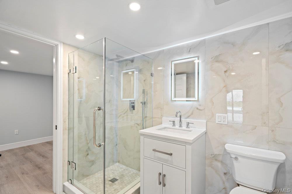 52 Woodland Road Roslyn, NY 11576 - Photo 10 of 23 a bathroom with a shower sink vanity mirror and toilet