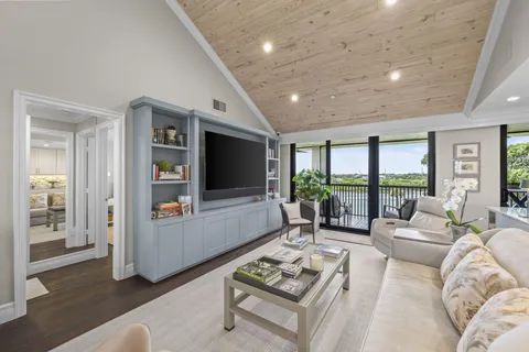 a living room with furniture floor to ceiling window and a flat screen tv