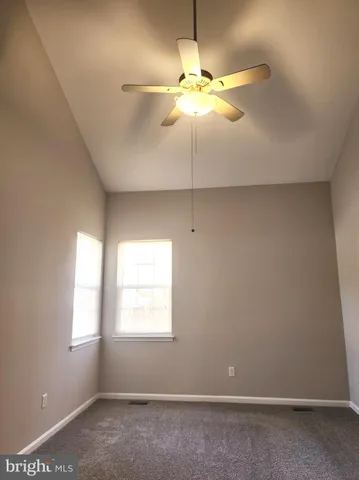 an empty room with a window and a chandelier fan