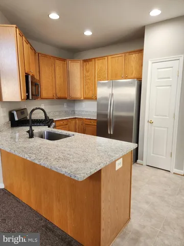 a kitchen with stainless steel appliances granite countertop a sink a refrigerator and a granite counter tops