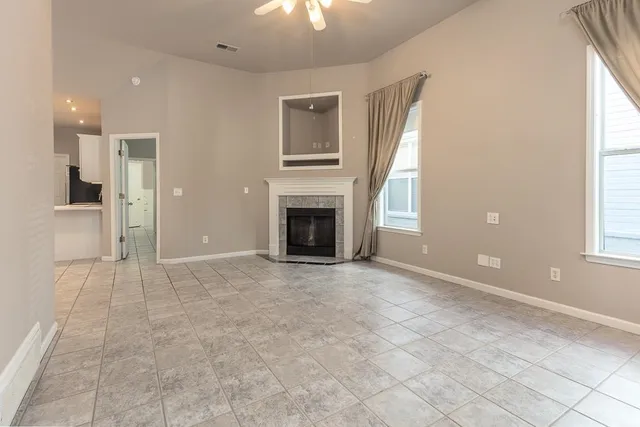 an empty room with windows and fireplace