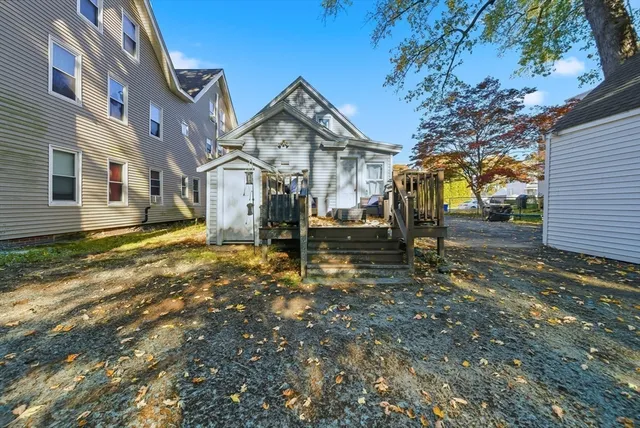 a view of a white house next to a yard with large trees