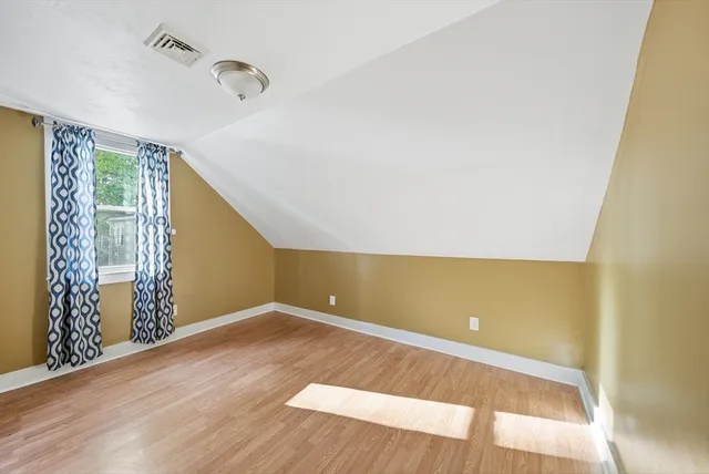 a view of an empty room with wooden floor and windows