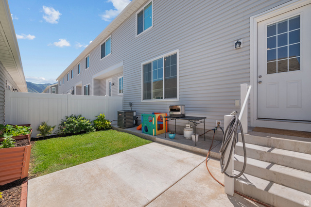 1693 North Center Point Lane Salem, UT 84653 - Photo 23 of 26 Rear exterior featuring light gray siding, white privacy fencing, concrete patio, grass lawn, and a raised planter box