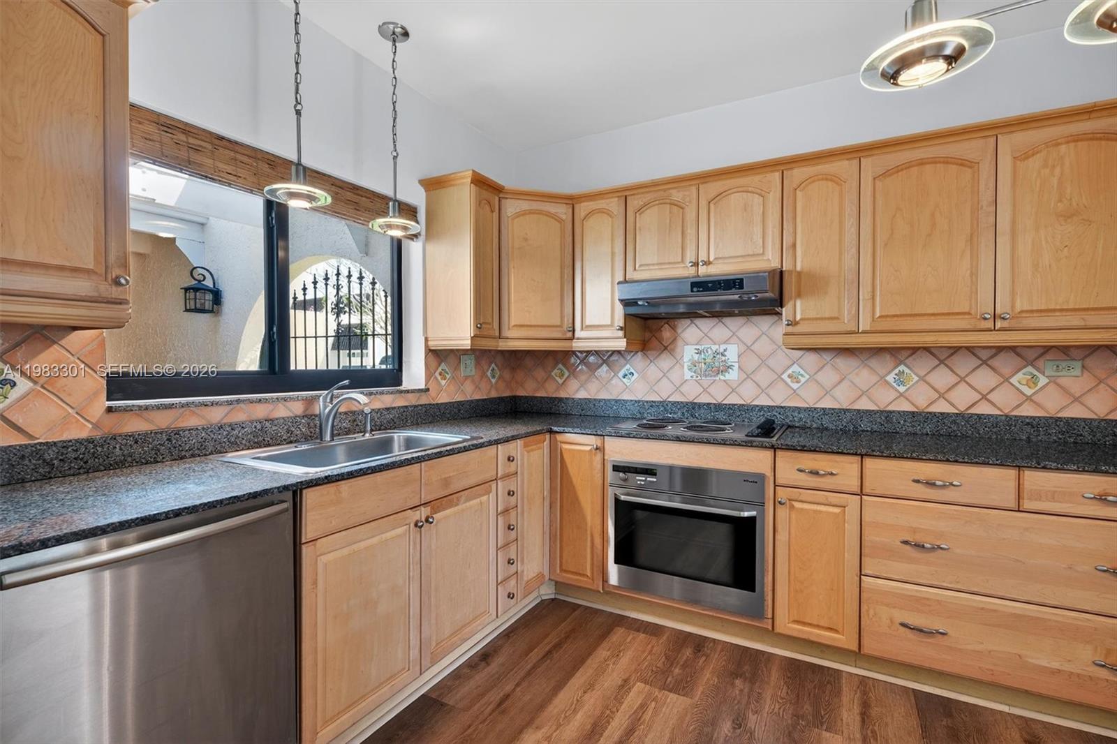 6190 Southwest 90th Court, Unit 1K Miami, FL 33173 - Photo 8 of 49 a kitchen with granite countertop a sink stainless steel appliances white cabinets and a wooden floor