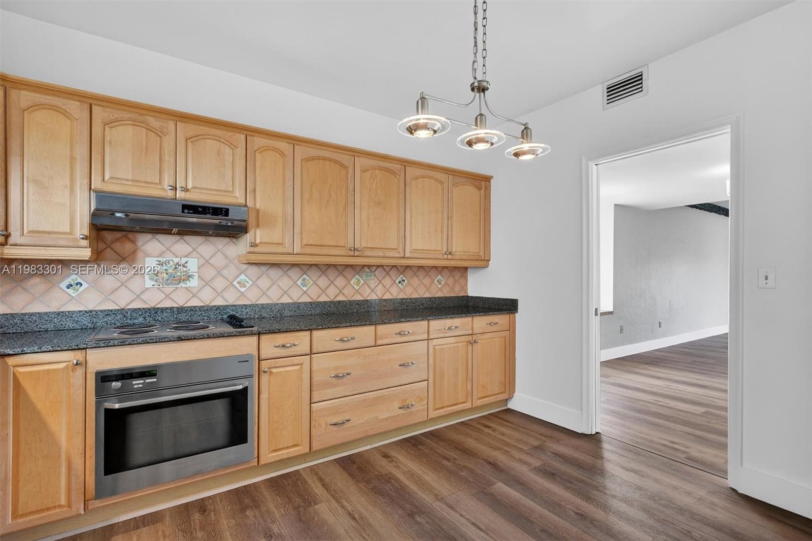 6190 Southwest 90th Court, Unit 1K Miami, FL 33173 - Photo 10 of 49 a kitchen with granite countertop cabinets stainless steel appliances and wooden floor