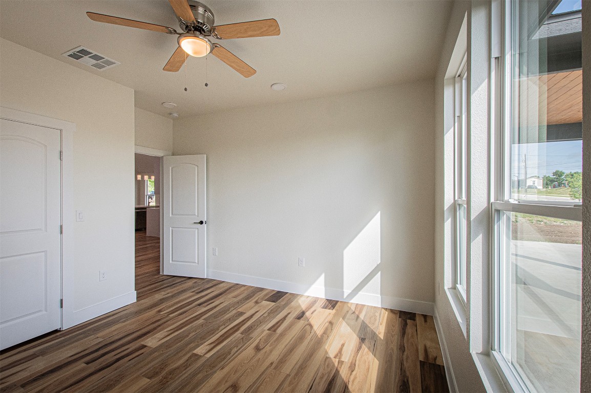 106 Passion Vine Rd Dale Dale, TX 78616 - Photo 14 of 23 a view of a bedroom with wooden floor a ceiling fan and windows