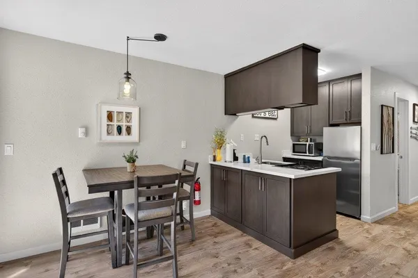 a kitchen with stainless steel appliances a table chairs and a refrigerator