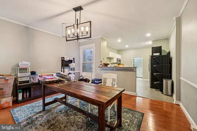 a living room with stainless steel appliances furniture a rug and a chandelier