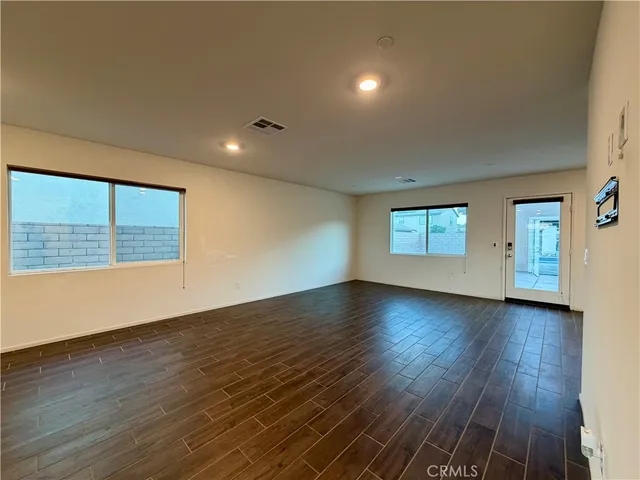 a view of an empty room with wooden floor and windows
