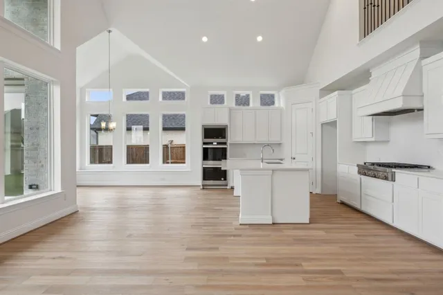 a large white kitchen with stainless steel appliances granite countertop a stove and a sink