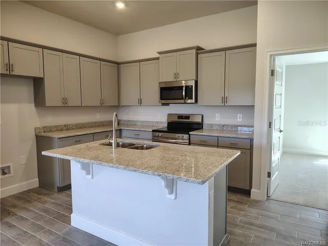 an empty room with wooden floor and stainless steel appliances