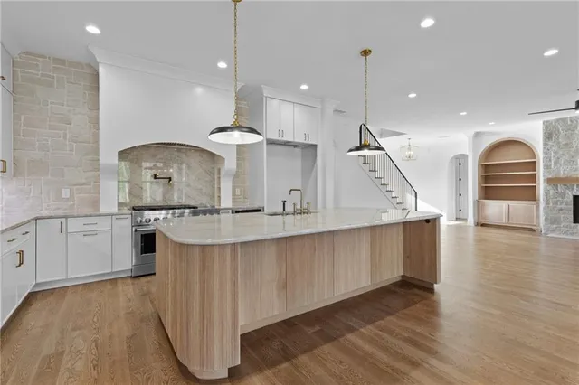 an empty room with wooden floor chandelier fan and windows