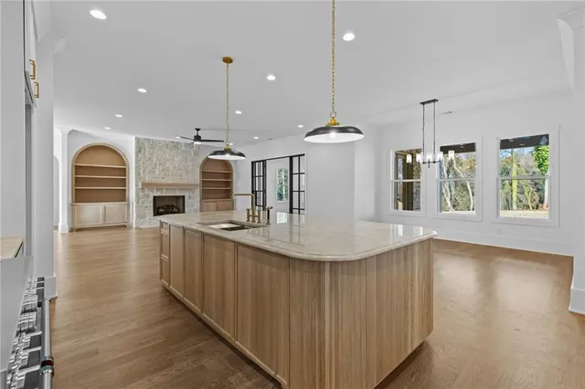 a view of an empty room with wooden floor and a ceiling fan