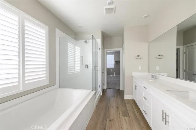 a spacious bathroom with a tub sink shower and two mirror