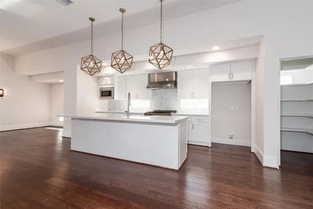 a very nice looking open with kitchen island white cabinets and wooden floor