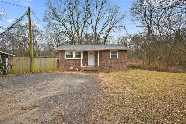 a view of a house with a yard and large tree