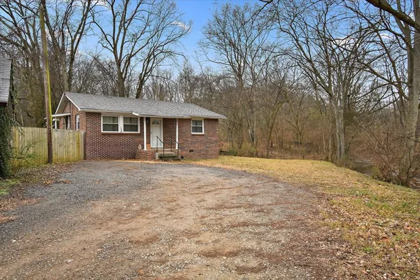 a front view of a house with a yard and large trees