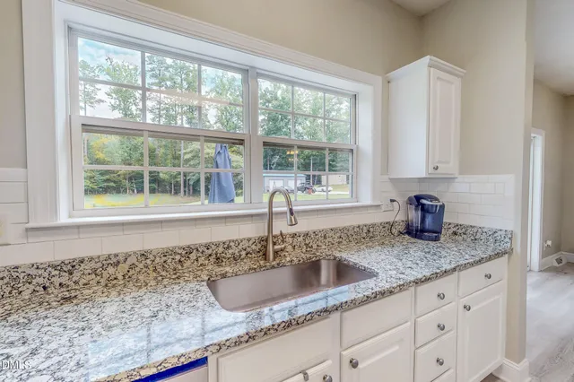 a kitchen with granite countertop white cabinets and a stove top oven