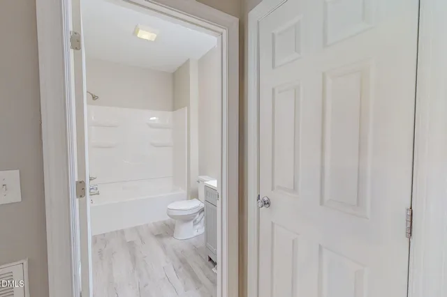 an empty room with wooden floor chandelier fan and windows