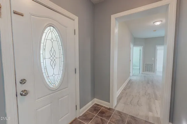 an empty room with wooden floor closet fan and windows