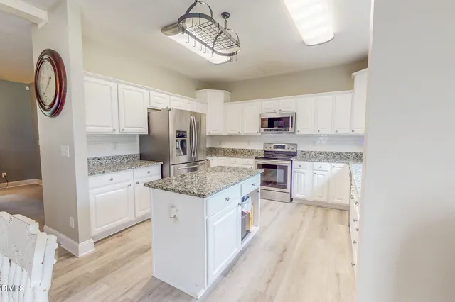 a kitchen with stainless steel appliances granite countertop a stove a sink and a refrigerator