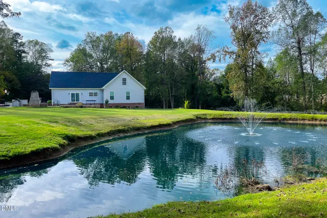 a view of a house with a yard and a large tree