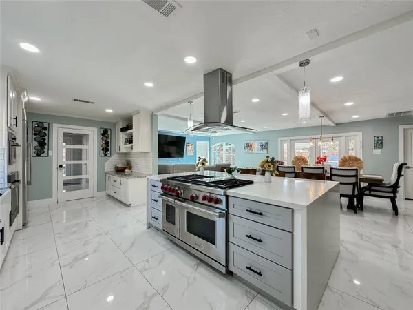 a kitchen with stainless steel appliances granite countertop a table chairs sink and cabinets