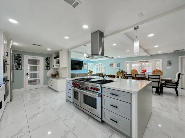 a kitchen with stainless steel appliances granite countertop a table chairs sink and cabinets
