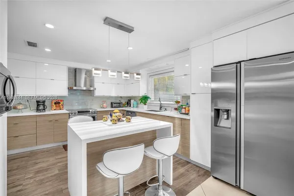 a kitchen with a refrigerator a sink cabinets and wooden floor