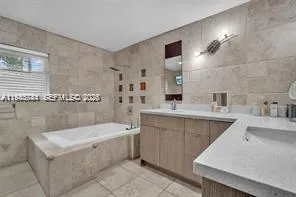 a bathroom with a sink tub double vanity and mirror
